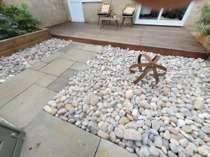 Garden landscaping project in Mells with Hardwood Balau Deck, Kandla Grey Sandstone Paving, Flowerbeds, Scottish Pebbles, and Slatted Fence Panels