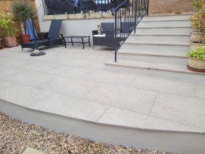 Porcelain patio installation in Midsomer Norton with ivory cream paving and steps, complemented by rendered walls for a bright and crisp finish