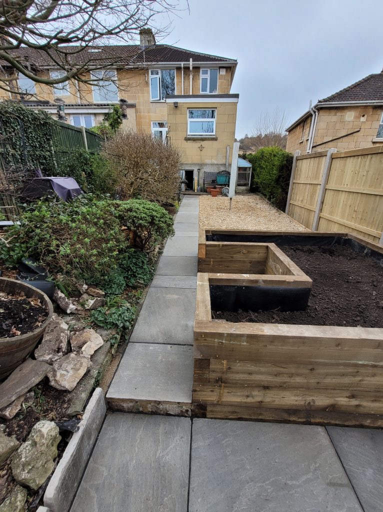 Beautifully landscaped garden in Bath with sandstone grey paving, raised planter, and fence panels